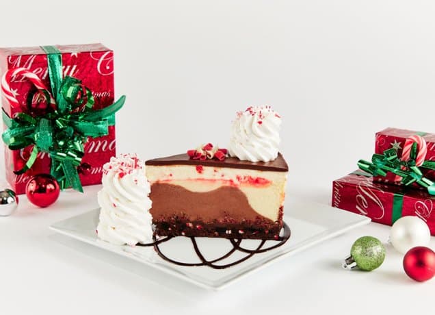 cheesecake factory peppermint stick chocolate swirl cheesecake: the cheesecake factory's peppermint stick chocolate swirl cheesecake on a plate next to christmas presents