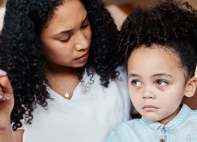 A mother gently talks to her very upset daughter