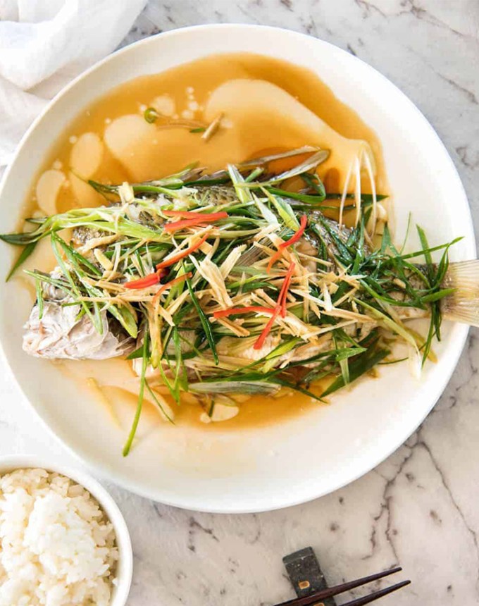 traditional chinese new year food: whole steamed fish in ginger-shallot sauce