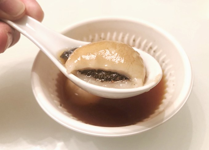 traditional chinese new year foods: Tāngyuán (Sweet Rice Ball) in a spoon above a sauce-filled bowl